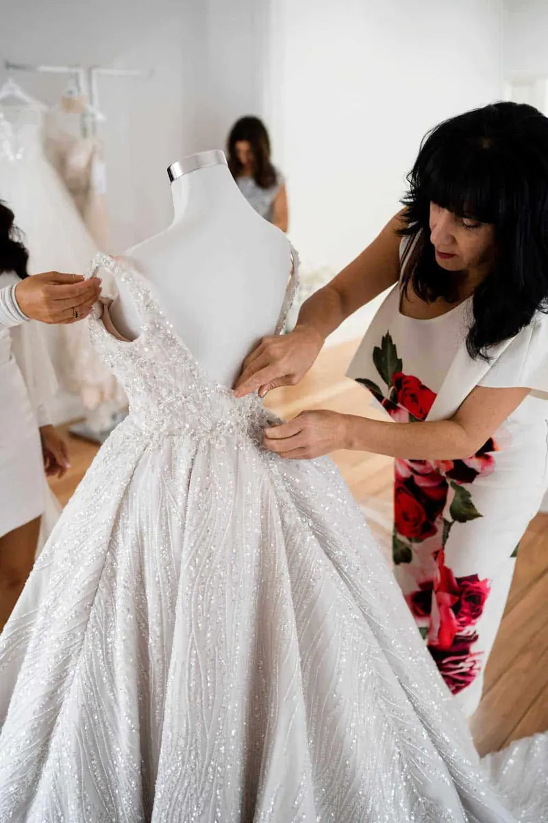 Catherine Colubriale adjusting a bespoke wedding gown in her atelier