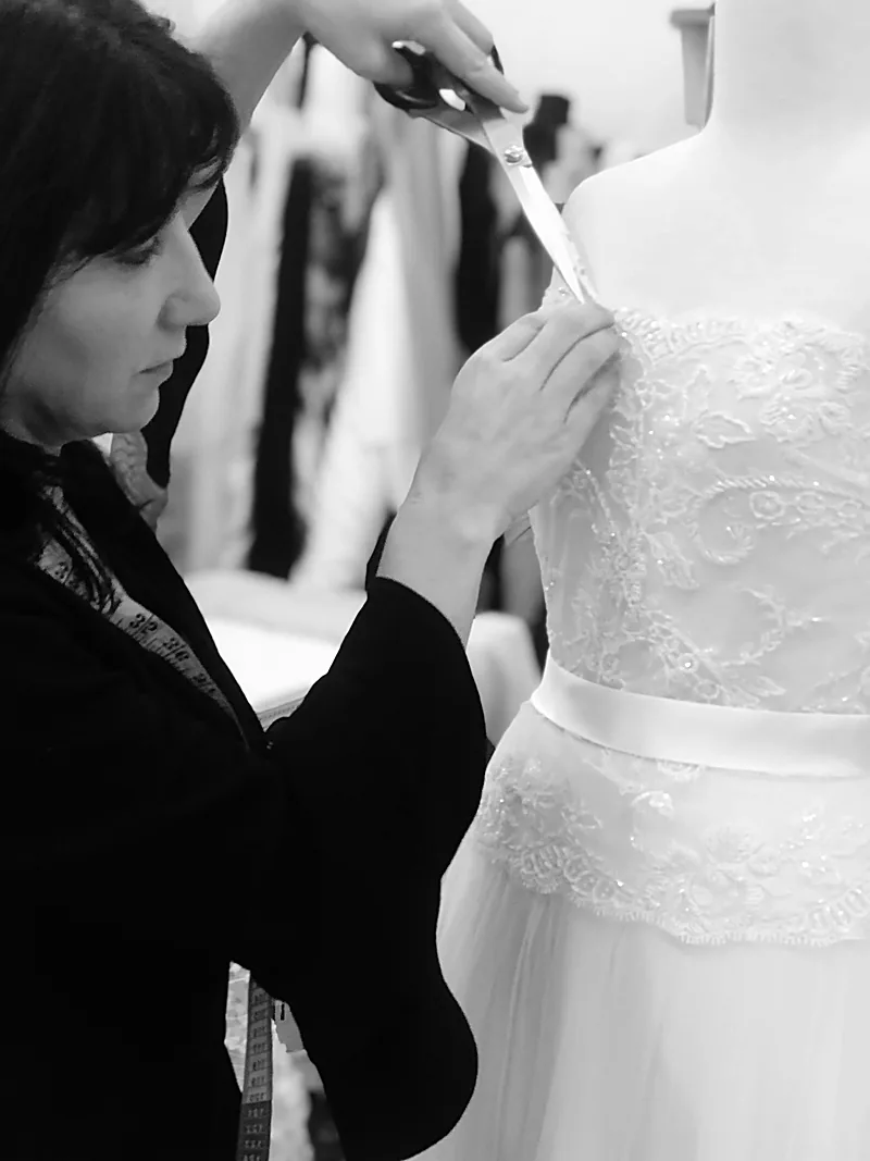 Catherine Colubriale finishing a lace bridal gown on the stand in her atelier
