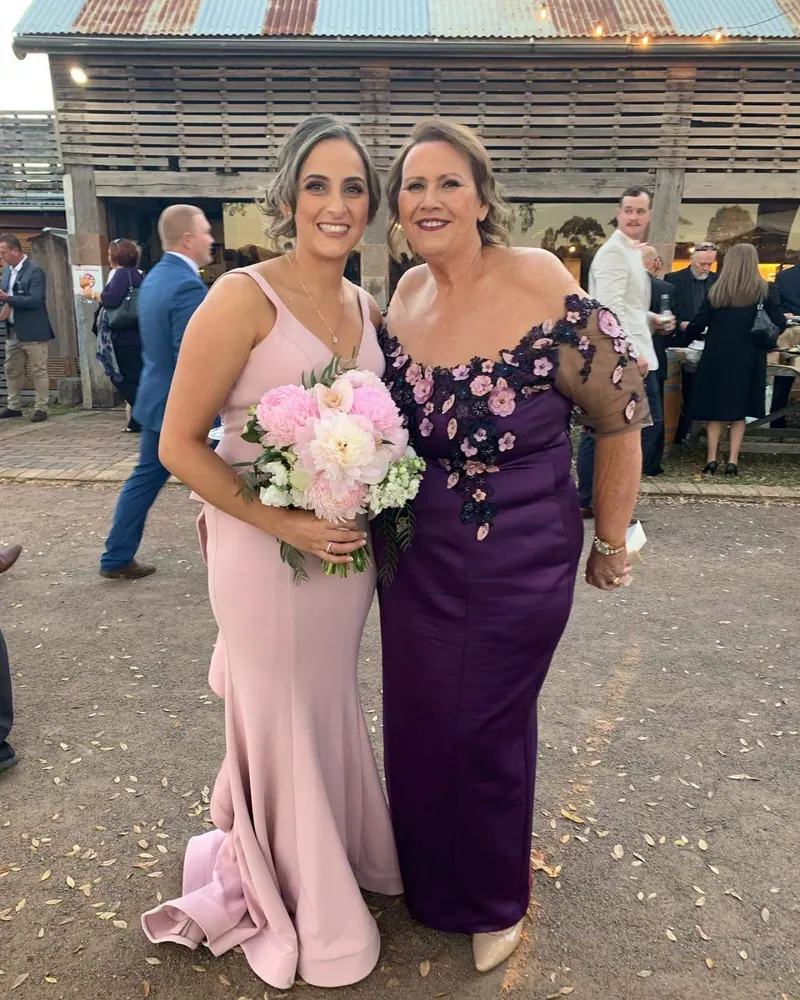 Mother of the bride in a bespoke plum gown with floral appliqué on sheer sleeves